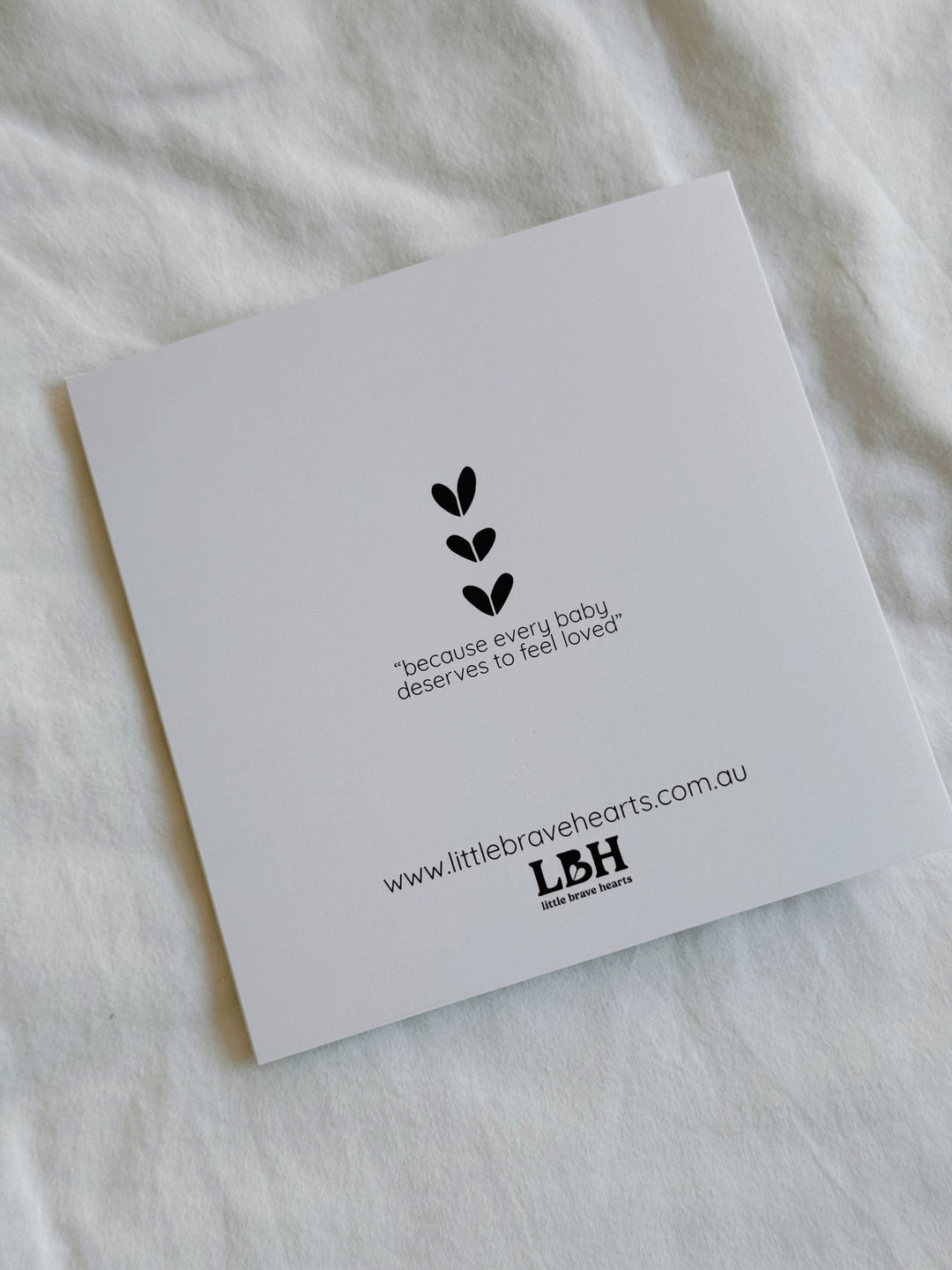 Hand holding a little girls birthday card with a bear illustration and 'Happy Birthday' text, with a blurred background. could be for first birthdays. 